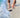 Person on a beach with feet in shallow water and a phone on the sand.