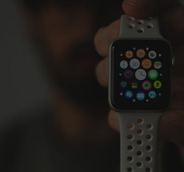 Smartwatch with a white band held by a person against a blurred background