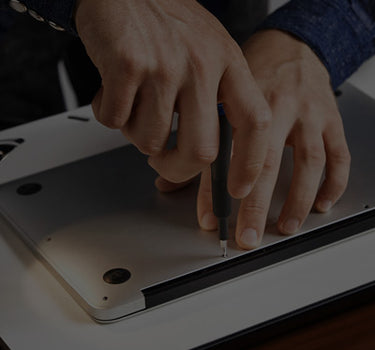 Person using a screwdriver on a laptop