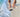Person on a beach with feet in shallow water and a phone on the sand.