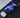 Smartphone with charging icon, wireless charger, and white case on a dark surface