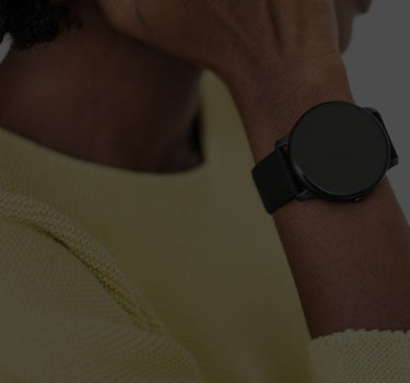 Person wearing a black smartwatch on a plain background