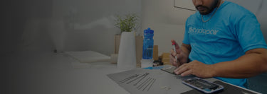 A technician wearing a blue iFixandRepair t-shirt fixing a cell phone on a table with precision tools