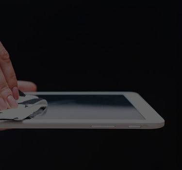 Person cleaning a tablet screen with a cloth on a black background