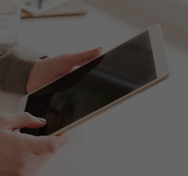 Person holding a tablet device on a light background