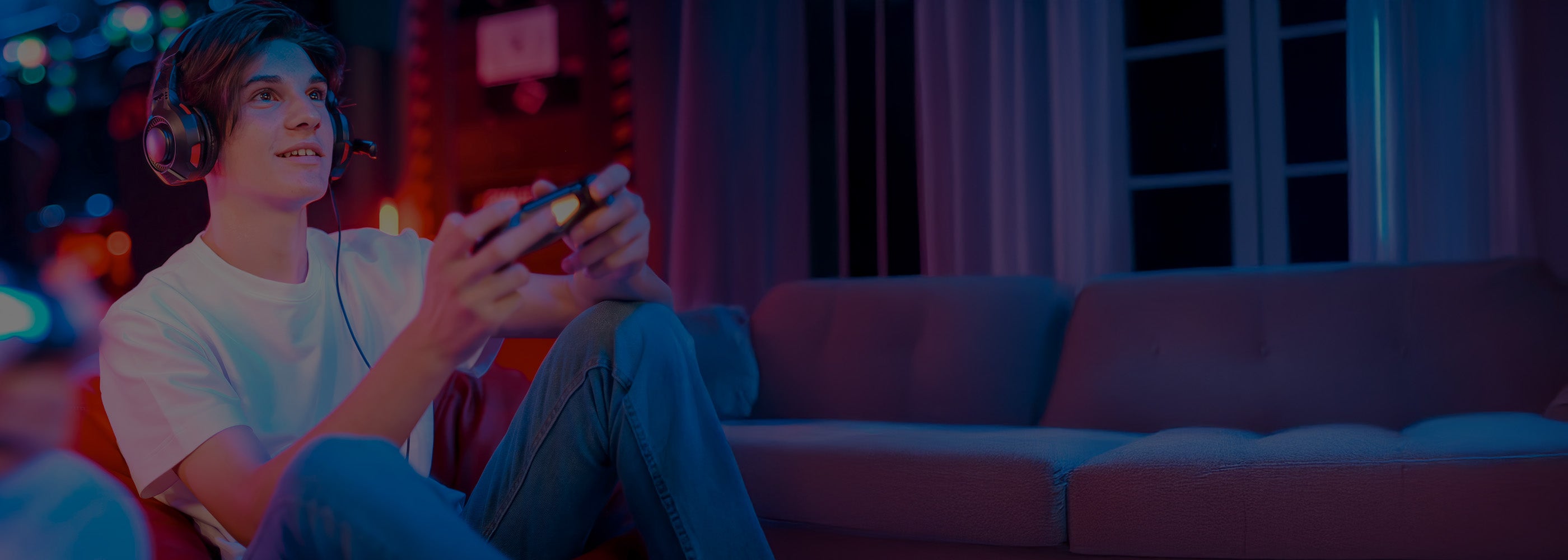 Person playing a video game with headphones on in a dark room with colorful lights.