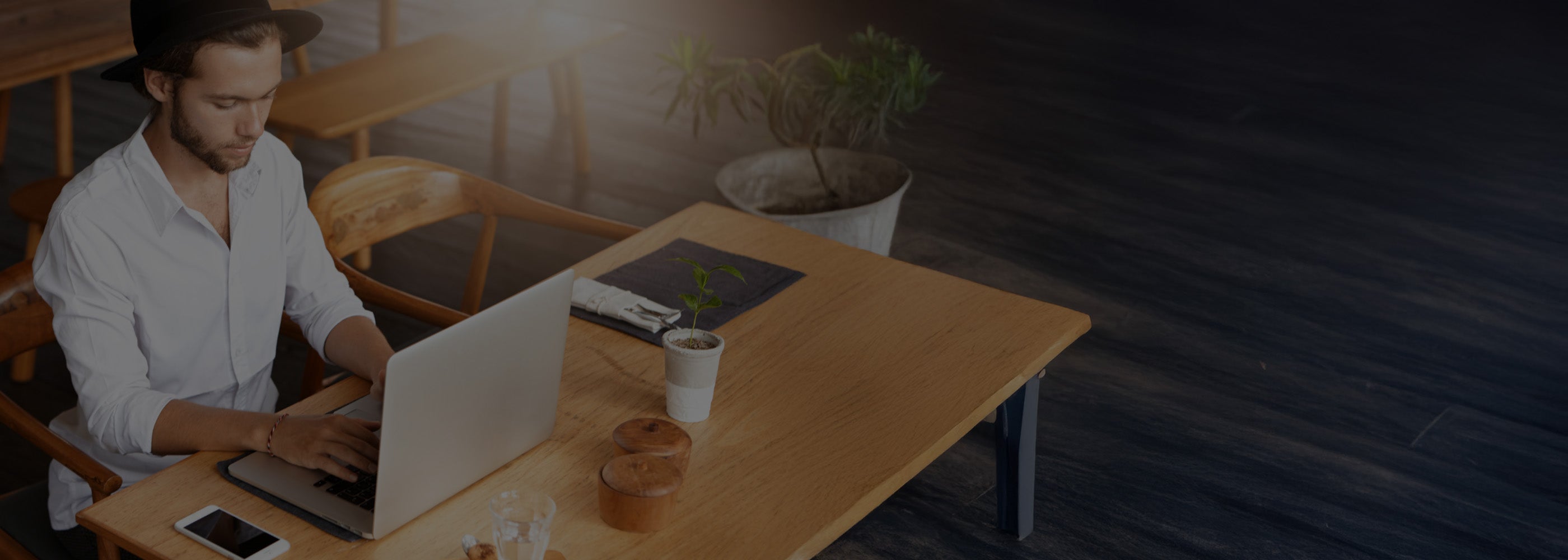 Man using a laptop at a wooden table in a casual setting
