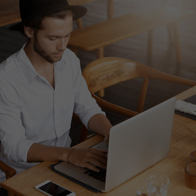 Man using a laptop at a wooden table in a casual setting