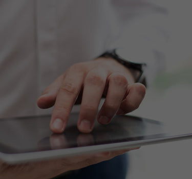 Hand holding a tablet device with a blurred background
