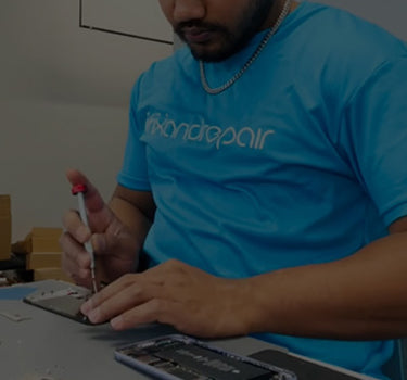 Technician in a blue t-shirt with iFixandRepair logo repairing a smartphone.