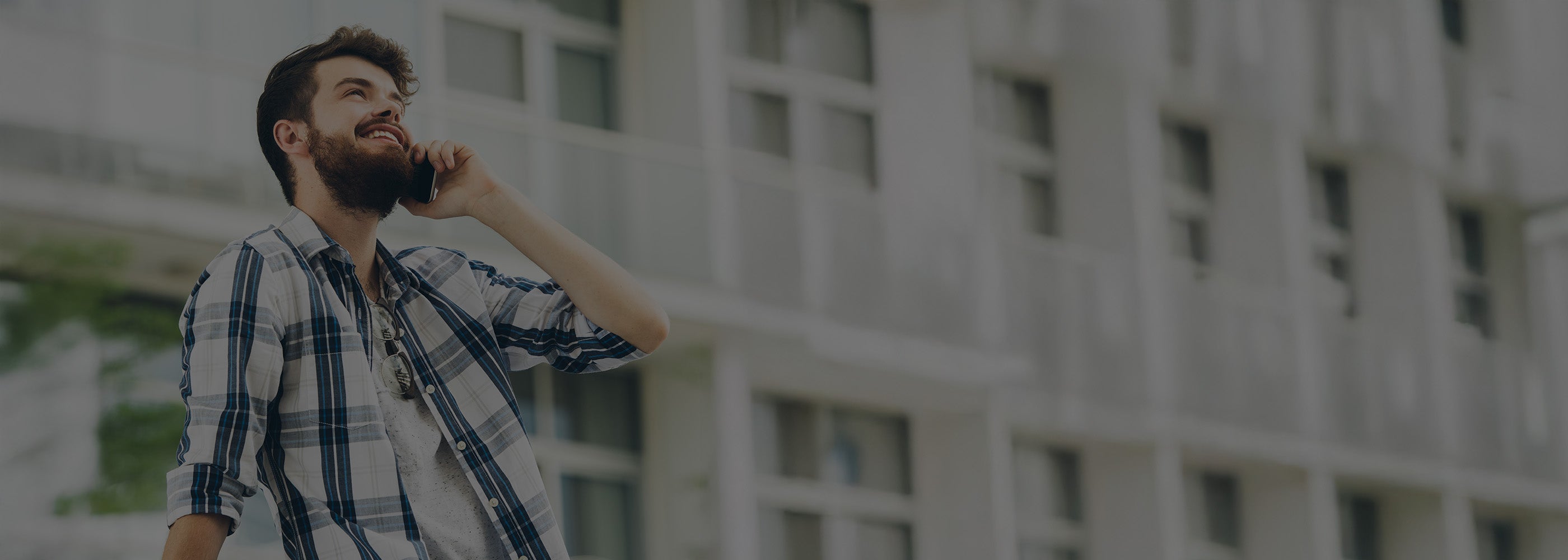 Man with a beard talking on a phone outdoors