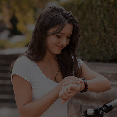 Woman adjusting her smartwatch outdoors with blurred background