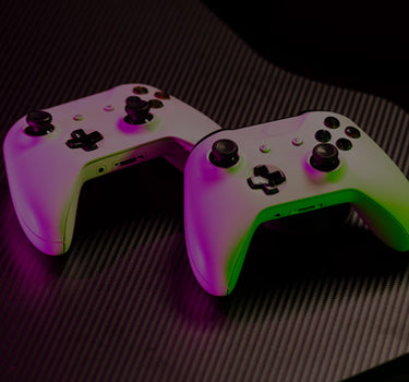 Two gaming controllers with a glowing effect on a dark surface