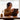 Woman using a tablet with headphones on, sitting at a table indoors.