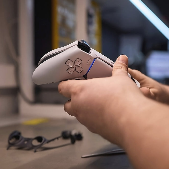 Hands holding a PlayStation 5 controller on a workbench