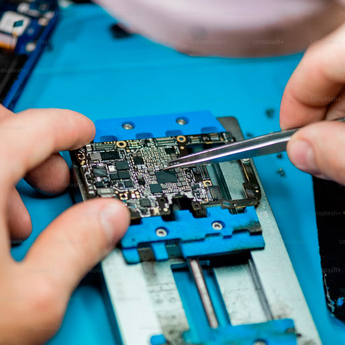 Close-up of technician repairing smartphone motherboard with precision tool