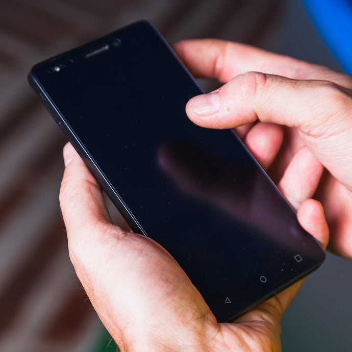 Hands holding a black smartphone with a blurred background
